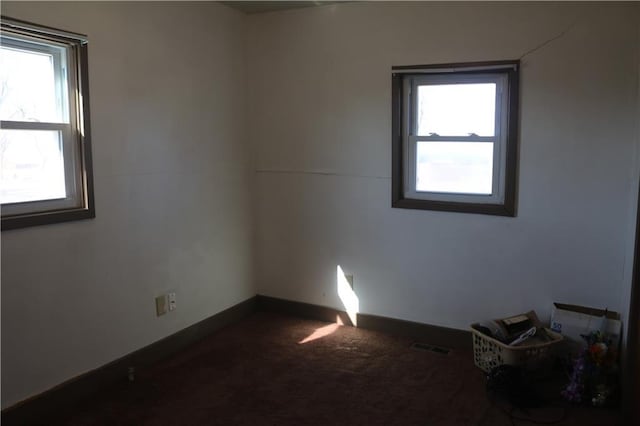 spare room with visible vents, baseboards, and dark carpet