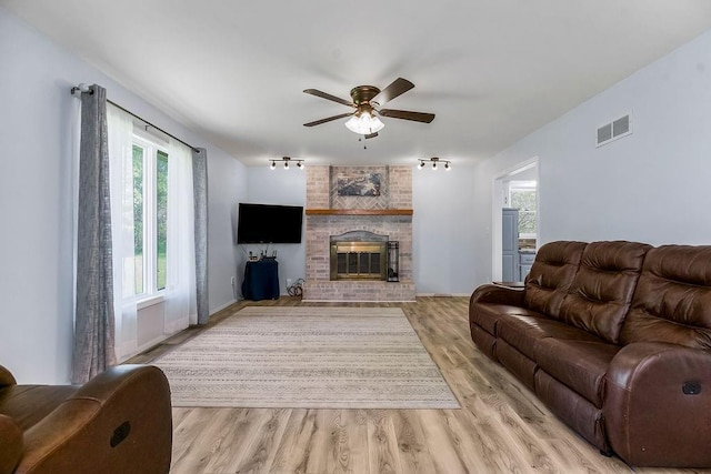 34701 E 235th St, Pleasant Hill, MO 64080 - living room with visible vents, a brick fireplace, ceiling fan, rail lighting, and light wood-style flooring