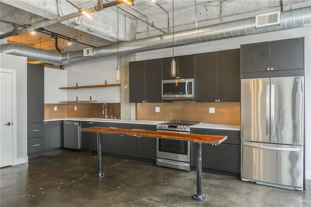 715 May St Unit 328, Kansas City, MO 64105 - kitchen featuring appliances with stainless steel finishes, concrete floors, light countertops, open shelves, and decorative backsplash