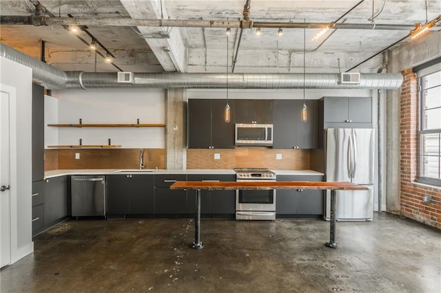 715 May St Unit 328, Kansas City, MO 64105 - kitchen featuring appliances with stainless steel finishes, open shelves, concrete floors, light countertops, and brick wall