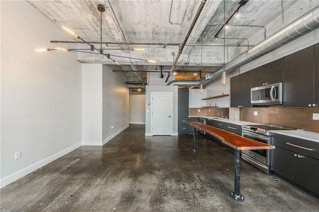 715 May St Unit 328, Kansas City, MO 64105 - kitchen with stainless steel appliances, finished concrete floors, backsplash, dark cabinetry, and open shelves