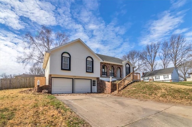 view of front of home with driveway, covered porch, fence, a garage, and a front yard