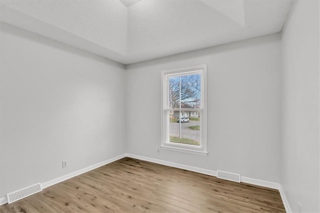 empty room with baseboards, wood finished floors, and visible vents