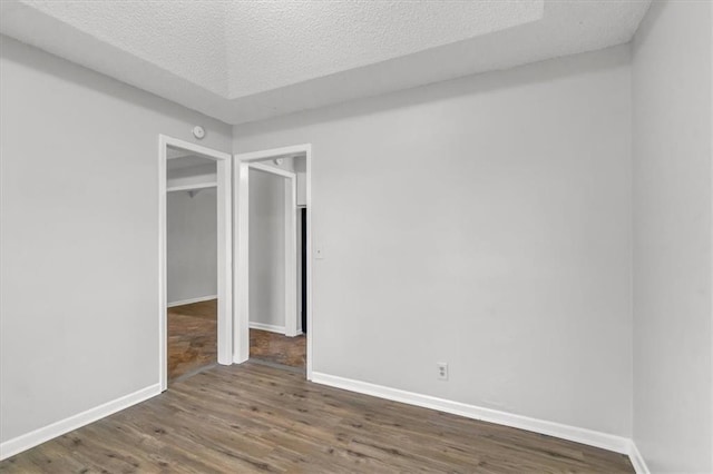 empty room featuring baseboards, wood finished floors, and a textured ceiling