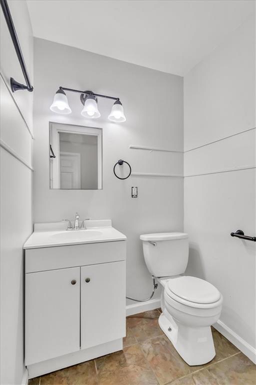 bathroom with baseboards, vanity, and toilet