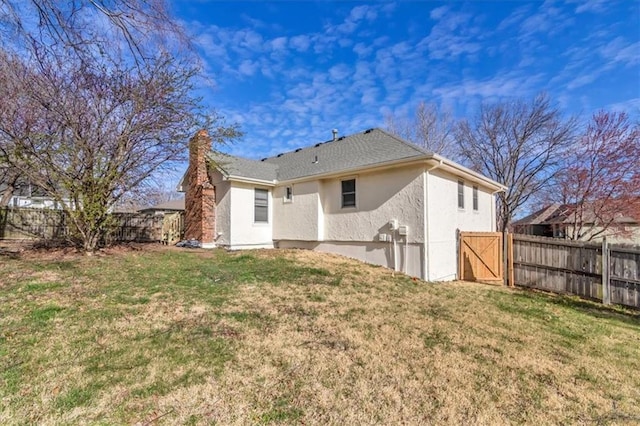 rear view of house featuring a lawn, a chimney, a fenced backyard, and stucco siding