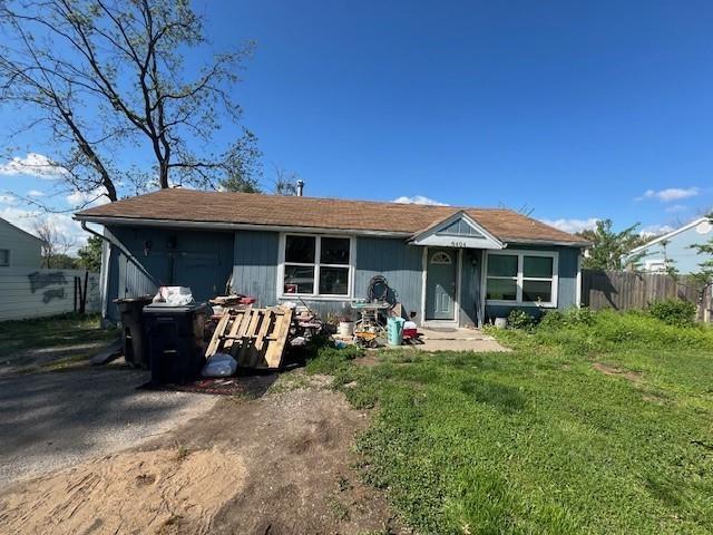 rear view of house with fence and a yard