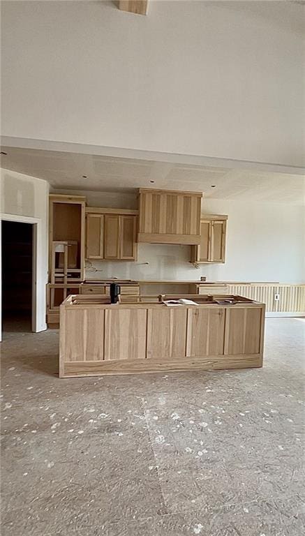 kitchen with a center island, a high ceiling, and light brown cabinetry