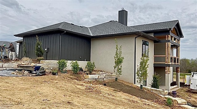 view of home's exterior with a shingled roof, stucco siding, and a chimney