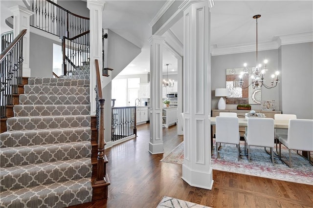 interior space with ornamental molding, decorative columns, wood finished floors, and a chandelier