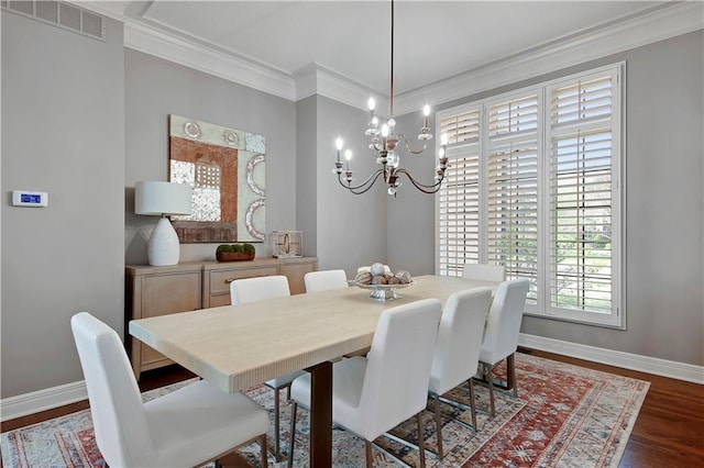 dining room featuring crown molding, a notable chandelier, baseboards, visible vents, and dark wood-style floors