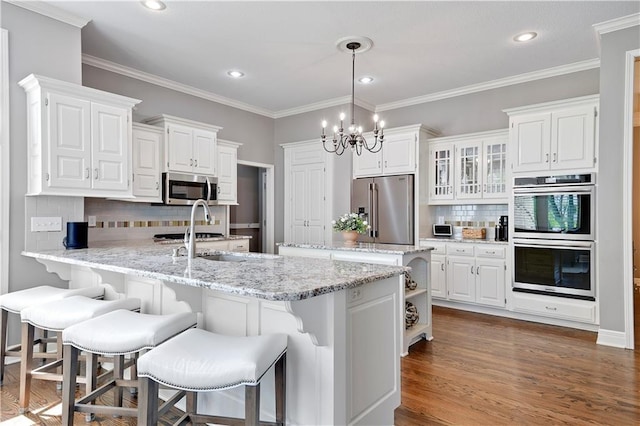 kitchen featuring an inviting chandelier, a peninsula, white cabinetry, tasteful backsplash, and stainless steel appliances