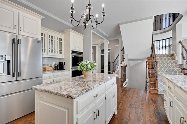 kitchen with a kitchen island, glass insert cabinets, tasteful backsplash, dark wood finished floors, and appliances with stainless steel finishes