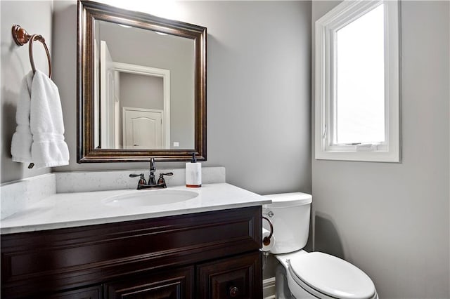 bathroom with plenty of natural light, toilet, and vanity