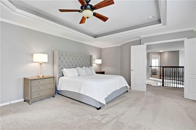 bedroom featuring crown molding, baseboards, ceiling fan, light colored carpet, and a tray ceiling