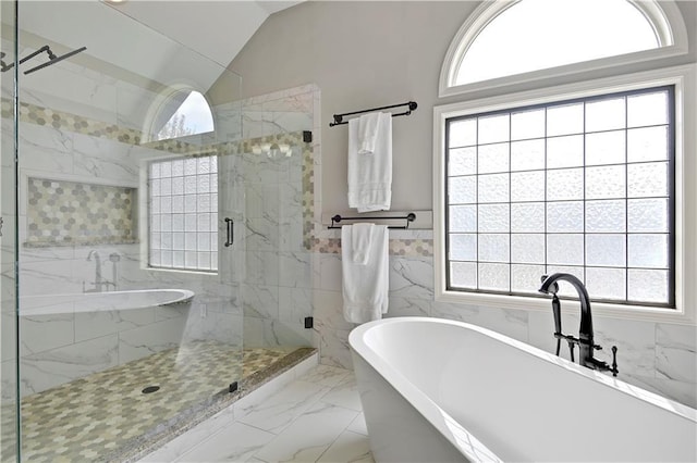bathroom with tile walls, marble finish floor, lofted ceiling, a marble finish shower, and a soaking tub