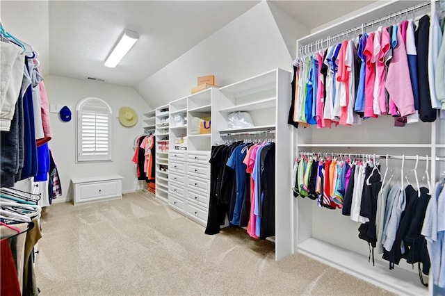 walk in closet with visible vents, carpet flooring, and vaulted ceiling