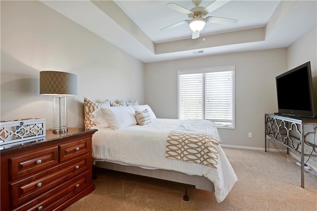 bedroom featuring visible vents, light carpet, baseboards, ceiling fan, and a tray ceiling
