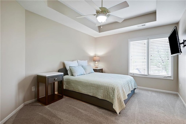 carpeted bedroom featuring visible vents, a ceiling fan, baseboards, and a tray ceiling