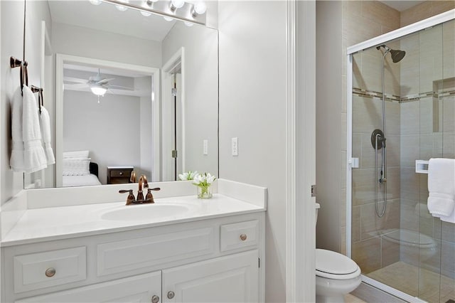 bathroom with toilet, ceiling fan, a shower stall, and vanity