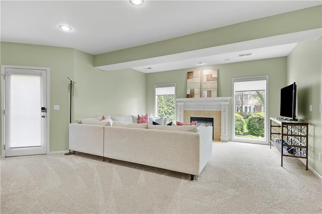 carpeted living area featuring baseboards, recessed lighting, a tiled fireplace, and a wealth of natural light