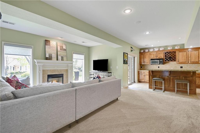 living area with recessed lighting, visible vents, light tile patterned floors, and a tile fireplace