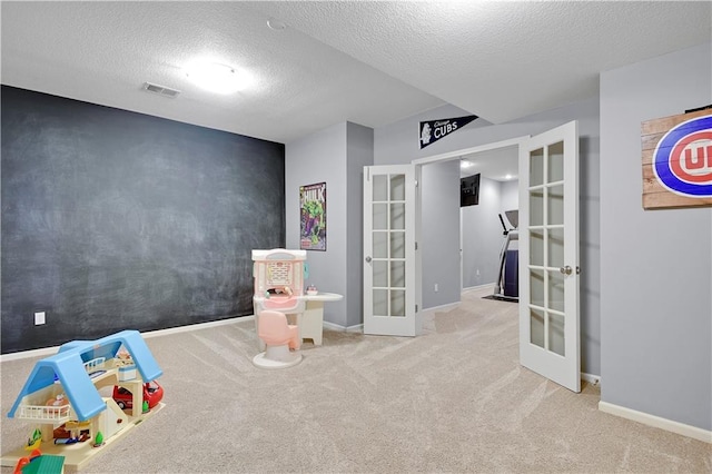 recreation room with french doors, a textured ceiling, visible vents, baseboards, and carpet