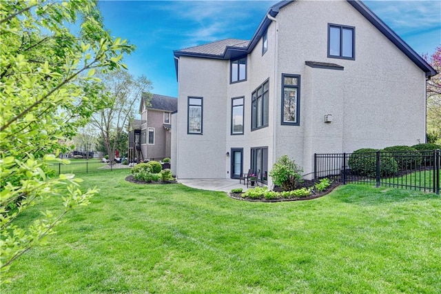 view of side of property with fence, a patio, stucco siding, and a lawn