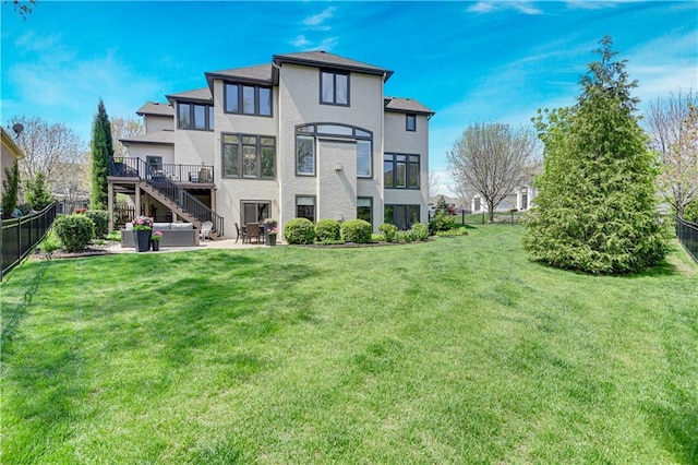 rear view of property featuring stucco siding, stairway, a fenced backyard, a patio area, and a lawn