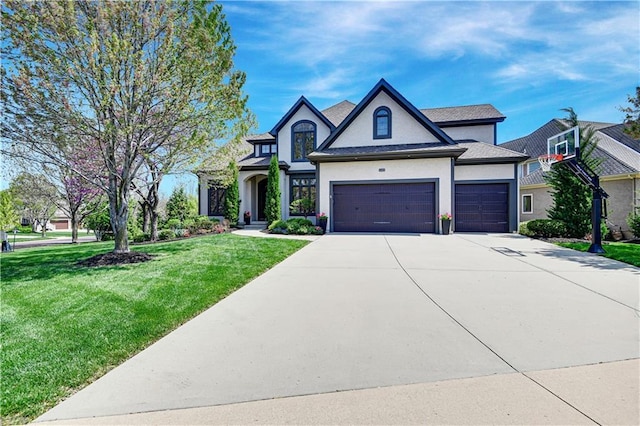view of front of property with stucco siding, an attached garage, driveway, and a front lawn
