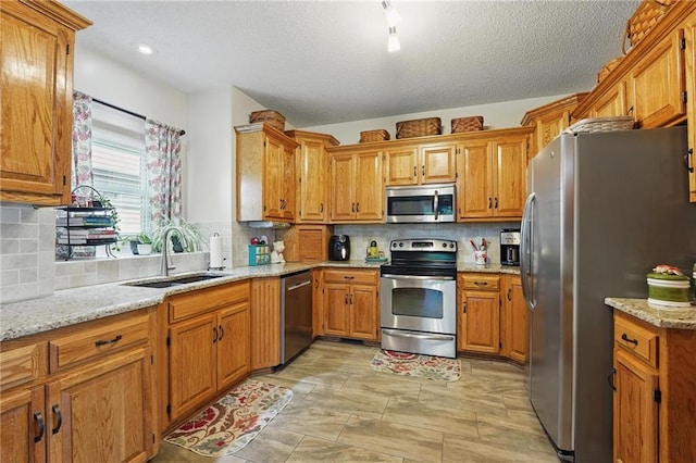 62 Beach Dr, Lake Tapawingo, MO 64015 - kitchen featuring appliances with stainless steel finishes, a sink, brown cabinets, decorative backsplash, and a textured ceiling