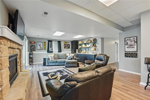62 Beach Dr, Lake Tapawingo, MO 64015 - living area featuring a drop ceiling, baseboards, light wood-type flooring, and a stone fireplace
