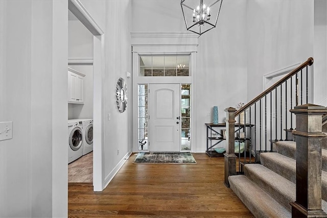 entryway featuring washing machine and clothes dryer, a high ceiling, an inviting chandelier, wood finished floors, and stairway
