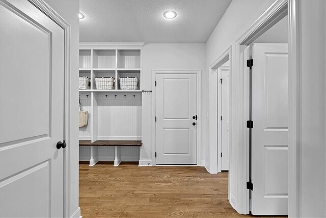 mudroom featuring light wood finished floors and a textured ceiling