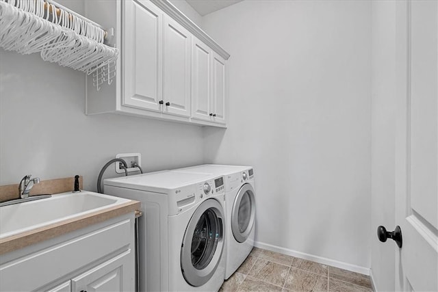 washroom featuring a sink, baseboards, cabinet space, and washer and dryer
