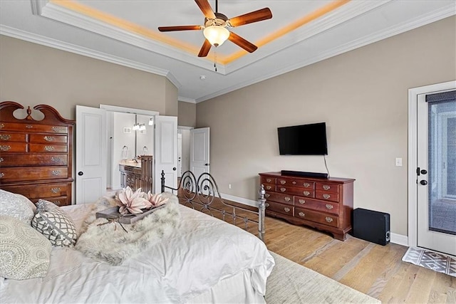 bedroom featuring baseboards, ornamental molding, wood finished floors, and a tray ceiling