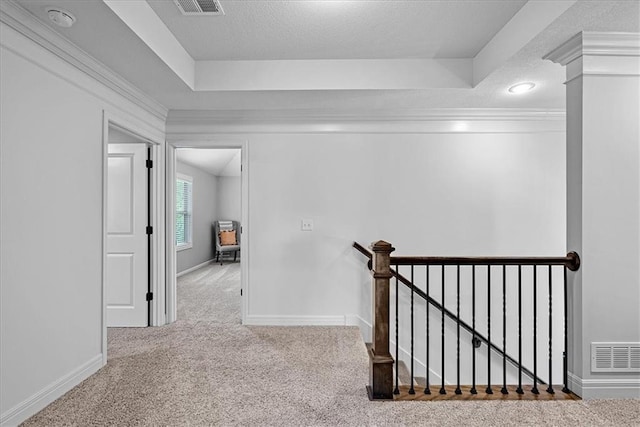 hallway with a textured ceiling, visible vents, carpet, and an upstairs landing