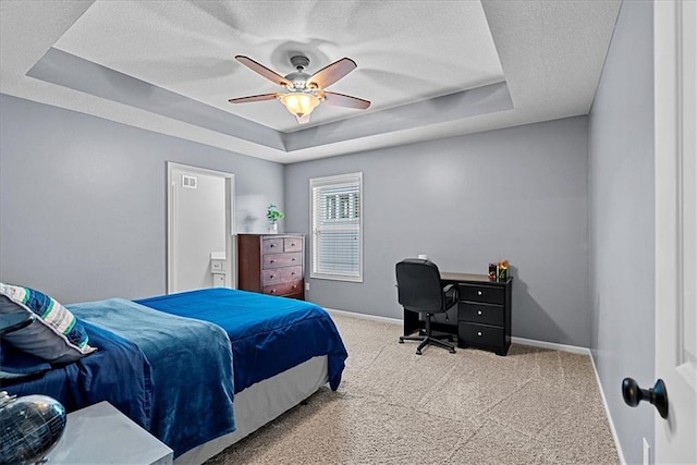 carpeted bedroom featuring baseboards, a ceiling fan, a tray ceiling, and a textured ceiling