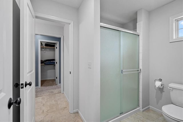 full bath with baseboards, a stall shower, a spacious closet, and toilet