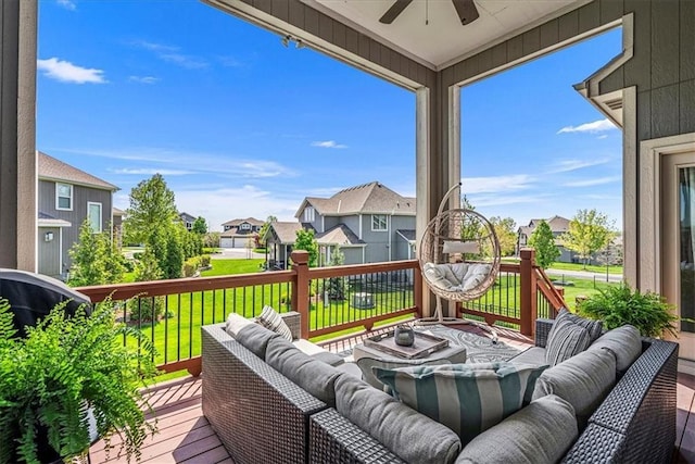 wooden terrace with an outdoor hangout area, a ceiling fan, a lawn, and a residential view