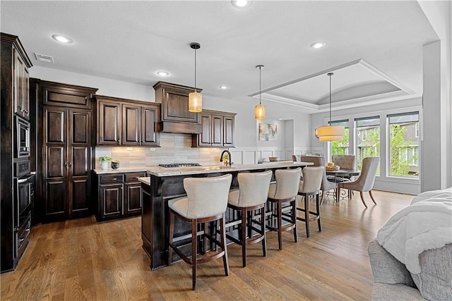 kitchen with visible vents, light countertops, open floor plan, a breakfast bar, and a tray ceiling