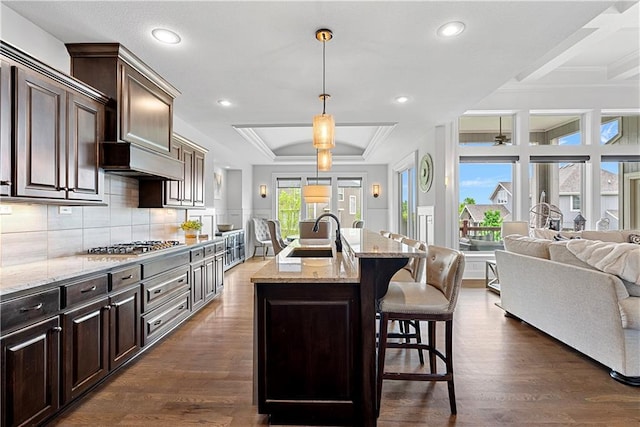 kitchen with ceiling fan, a kitchen bar, a sink, light stone counters, and open floor plan