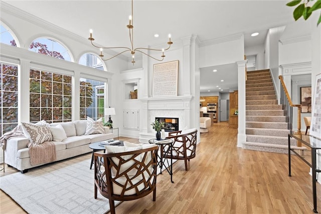 14215 W 157th Ter, Olathe, KS 66062 - living room with crown molding, a glass covered fireplace, light wood-style floors, stairs, and a chandelier