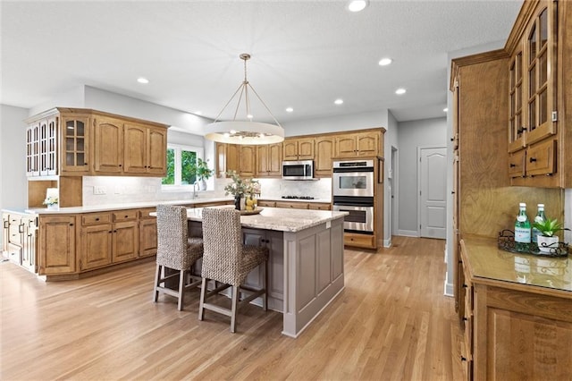 14215 W 157th Ter, Olathe, KS 66062 - kitchen featuring appliances with stainless steel finishes, a center island, brown cabinetry, a breakfast bar area, and recessed lighting