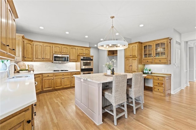 14215 W 157th Ter, Olathe, KS 66062 - kitchen with a sink, appliances with stainless steel finishes, a center island, a kitchen bar, and light wood finished floors