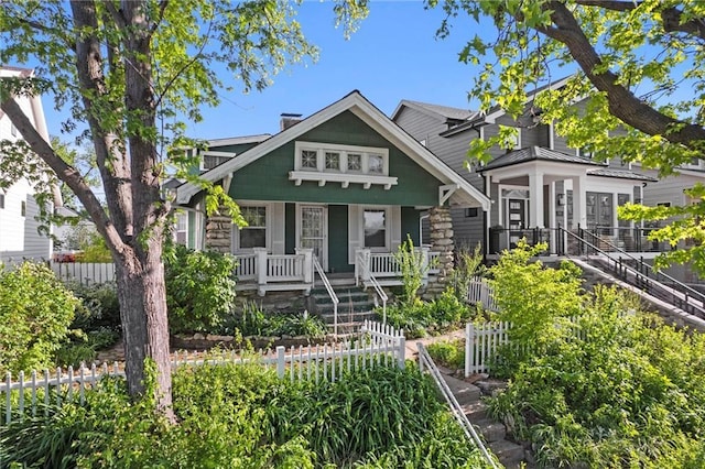 view of front of home with a porch, fence, and stairs