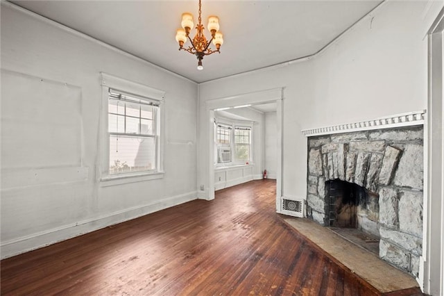 unfurnished living room featuring a stone fireplace, visible vents, baseboards, wood-type flooring, and a chandelier