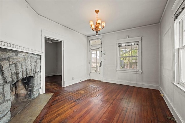 interior space featuring baseboards, a notable chandelier, a stone fireplace, and hardwood / wood-style flooring