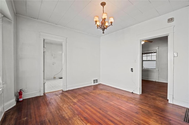 empty room with crown molding, visible vents, hardwood / wood-style flooring, and a notable chandelier