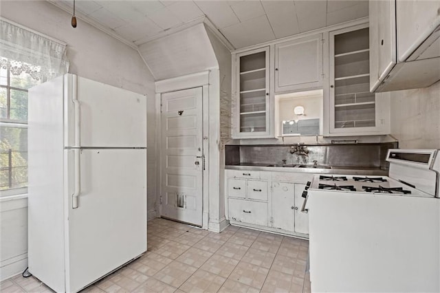 kitchen with tasteful backsplash, a sink, white cabinets, glass insert cabinets, and white appliances
